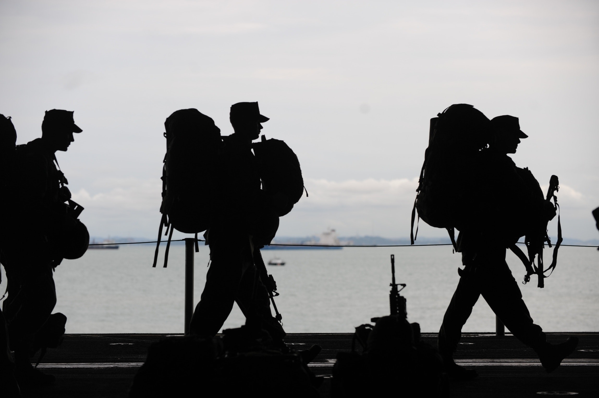 silhouettes of military personnel walking with campaign bags  